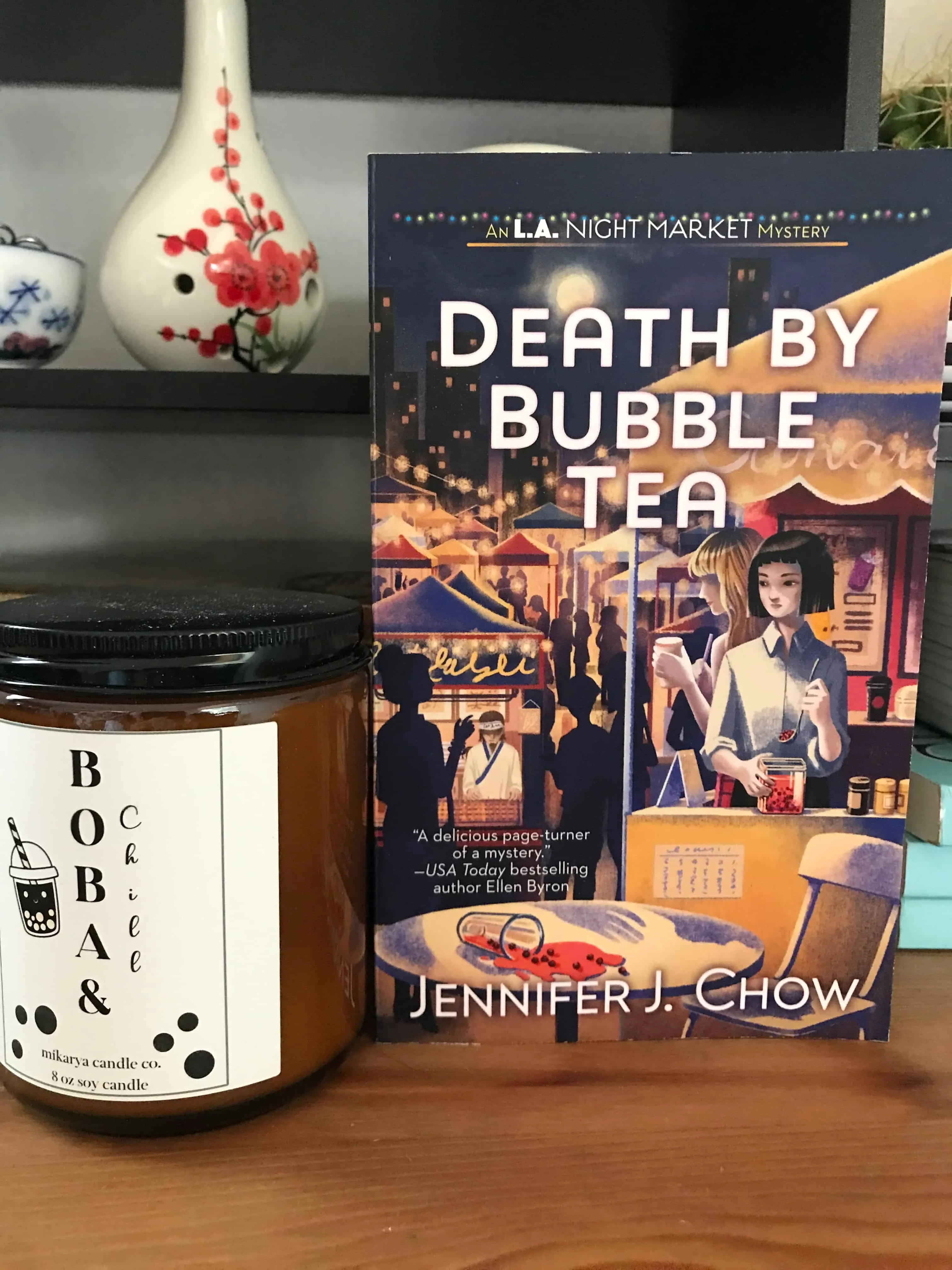 Jennifer J Chow's boba candle, beside a paperback of Death By Bubble Tea.